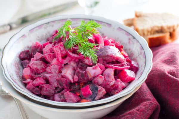 Festlich angerichteter Rollmops-Salat mit roter Bete, Apfel und Dill, serviert in einer dekorativen Schale.